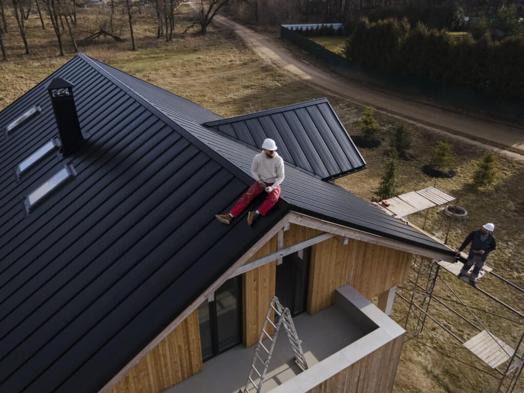Travailleurs sur le toit d'une maison moderne avec échelle.