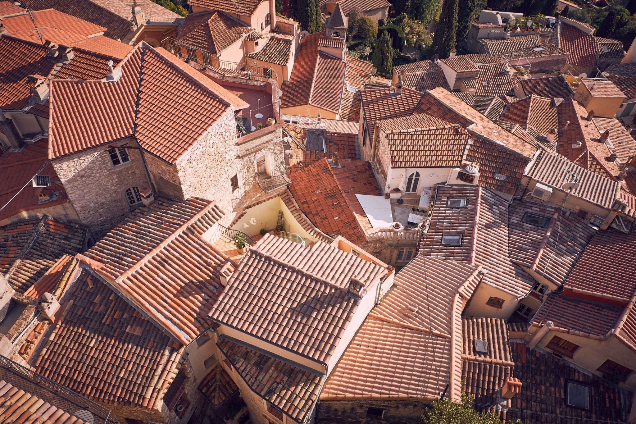 Vue aérienne de toits de tuiles rouges dans une commune.